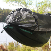 DD Hammocks Superlight Jungle Hammock with detachable mosquito net set up near a lake.